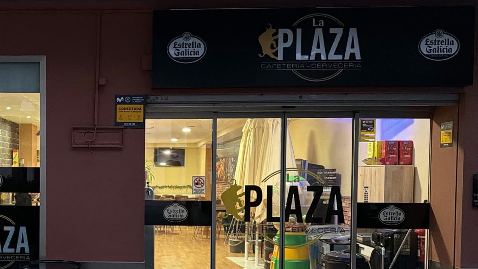 La entrada de La Plaza de noche, con el rótulo encendido sobre la puerta, en la calle Don Víctor de Tomelloso